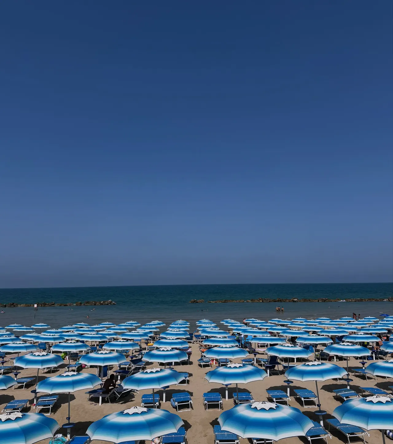 Rows of blue and white beach umbrellas under a wide open sky