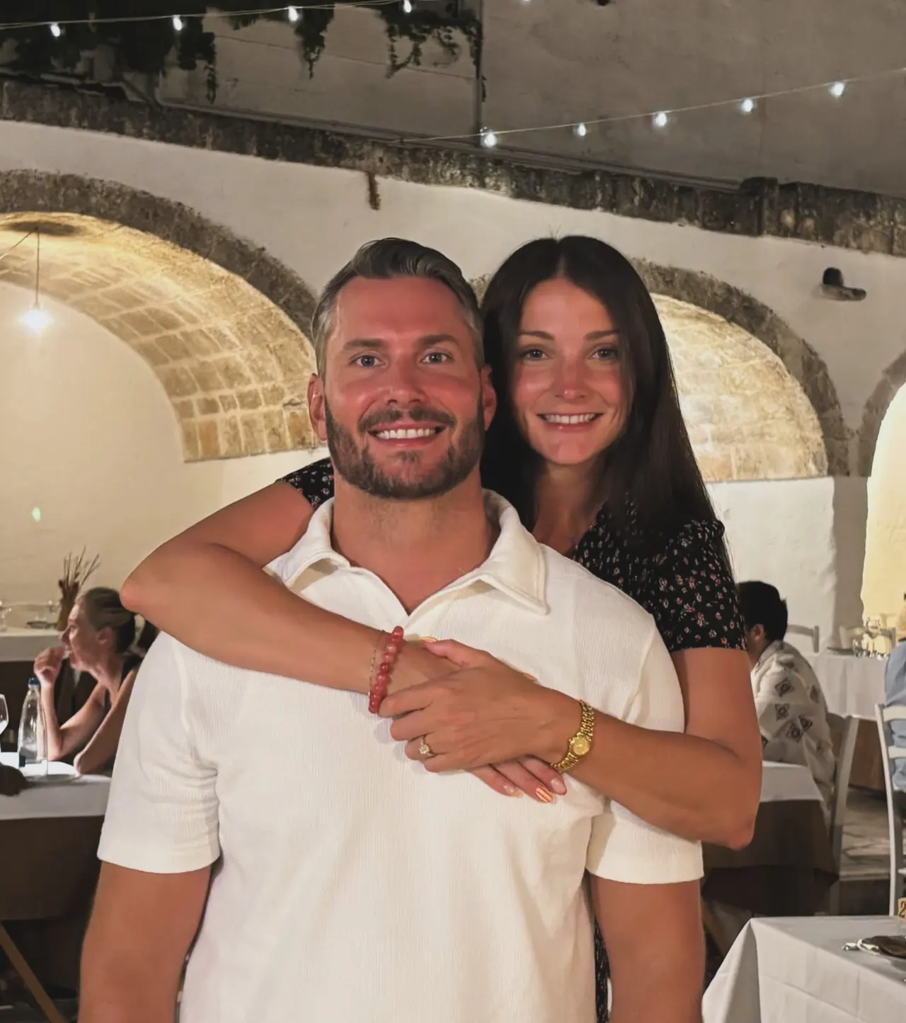 Drew and Valerie embracing in a vaulted stone restaurant at night